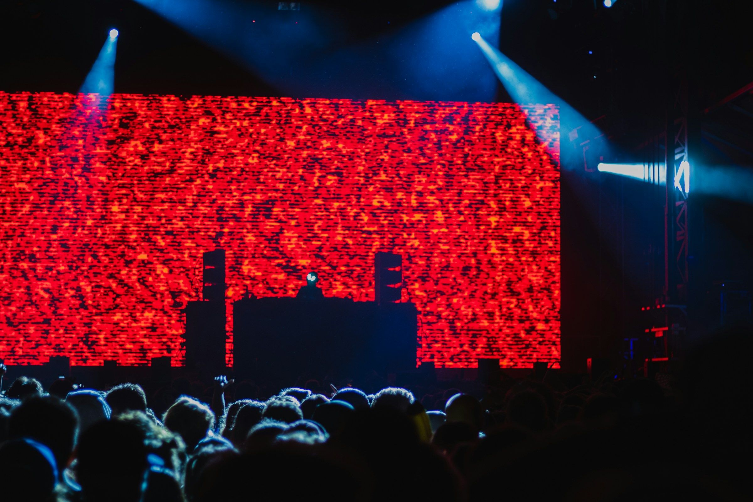 Cabina de DJ frente a una pantalla LED roja gigante y el público